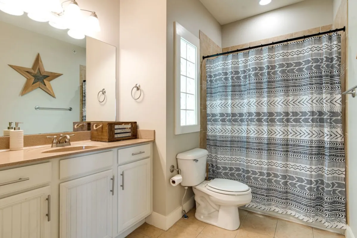 A fresh and inviting bathroom setting featuring a large mirror, decorative star, and textured shower curtain. The space is styled for personal grooming and self-care, with a calming atmosphere.