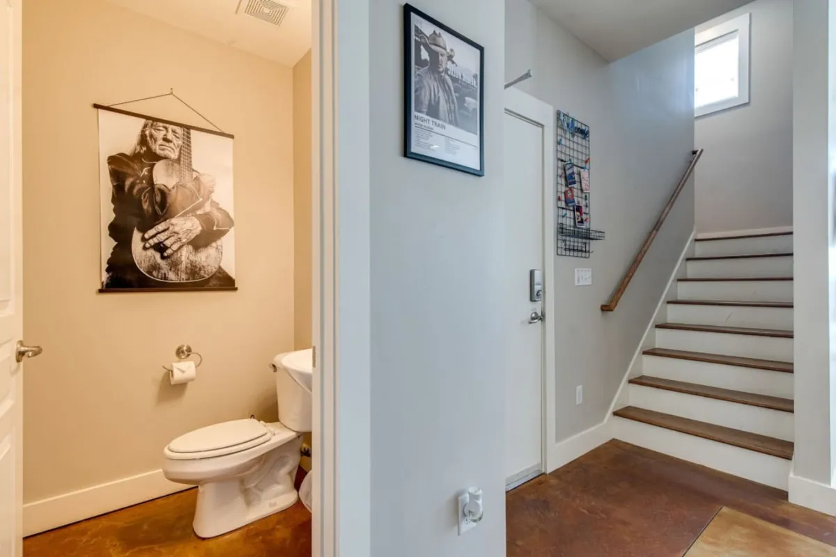 The image captures the entryway, adorned with striking black-and-white art and a decorative staircase ascending to upper levels. The space is welcoming and reflects a blend of security and style, providing a glimpse of the passage from entry to the interior of the condo.
