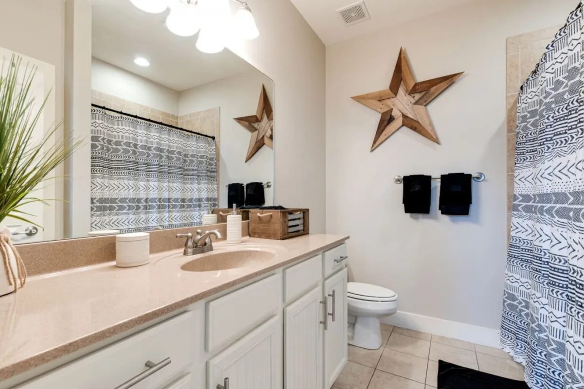 A bright, calming bathroom highlighted by a wooden star decor, striped shower curtain, and a sink with modern faucet. The clean lines and soothing color palette evoke a spa-like feeling—perfect for daily routines or a tranquil soak.